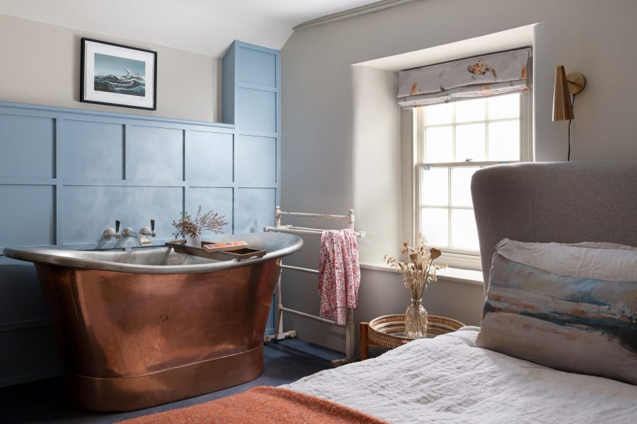 Photo of bedroom, featuring blue wall, copper bath tub, Georgian window and bed. A cottage in Port Isaac available for October Half Term 2023.