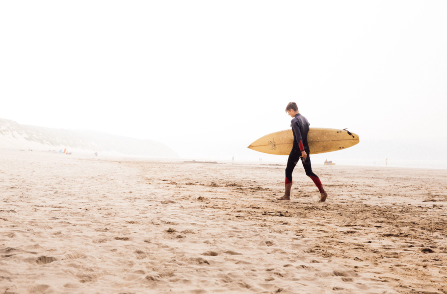 A surfer walking out to sea