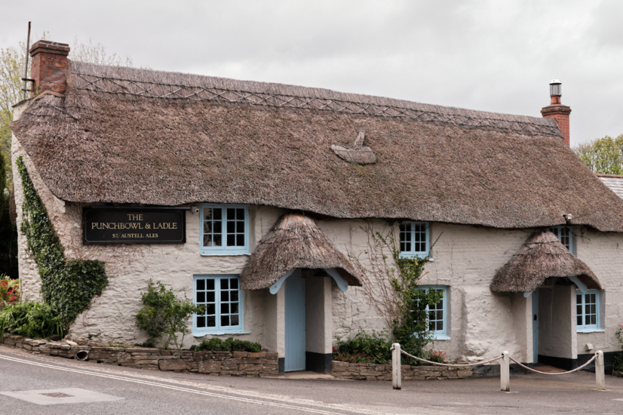 Punchbowl and Ladle pub in Feock Cornwall, thatch-roofed pub with blue windows and doors.