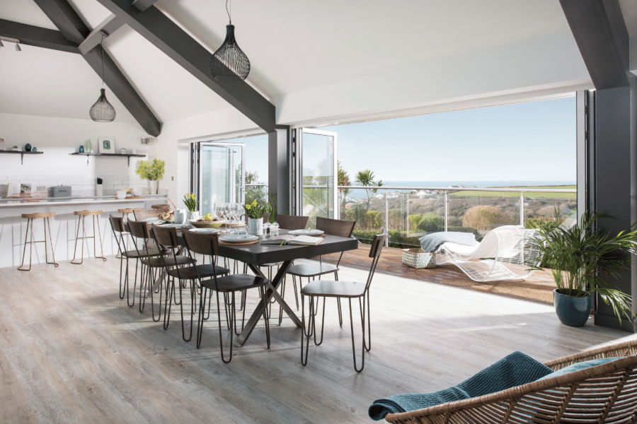 Open plan living space with open bi-fold windows leading out to terrace home in Cornwall to rent via Cornish Gems in Porthtowan