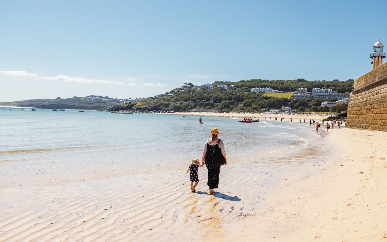 Easter holidays 2024 in Cornwall mum and child walking along sunny beach in St Ives